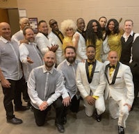 a group of people in white suits posing for a photo